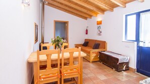 A cozy room with a wooden dining table, chairs, a sofa, and a covered bench. - Digne Orange Villa, Pool, BBQ (Rogil, Aljezur)