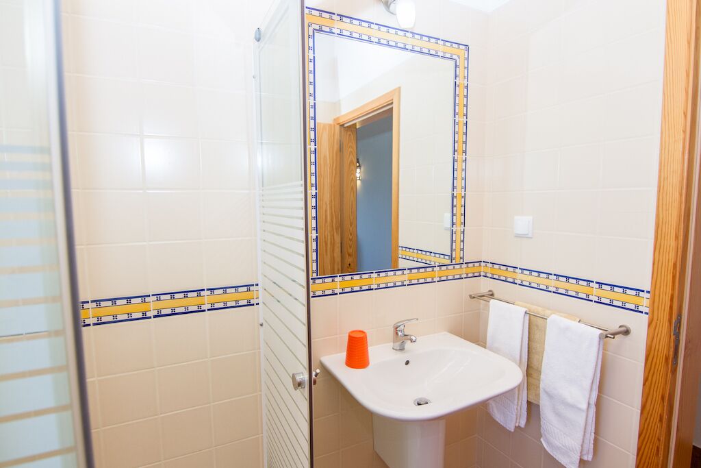 Une salle de bain avec un lavabo blanc, un miroir et un espace douche.