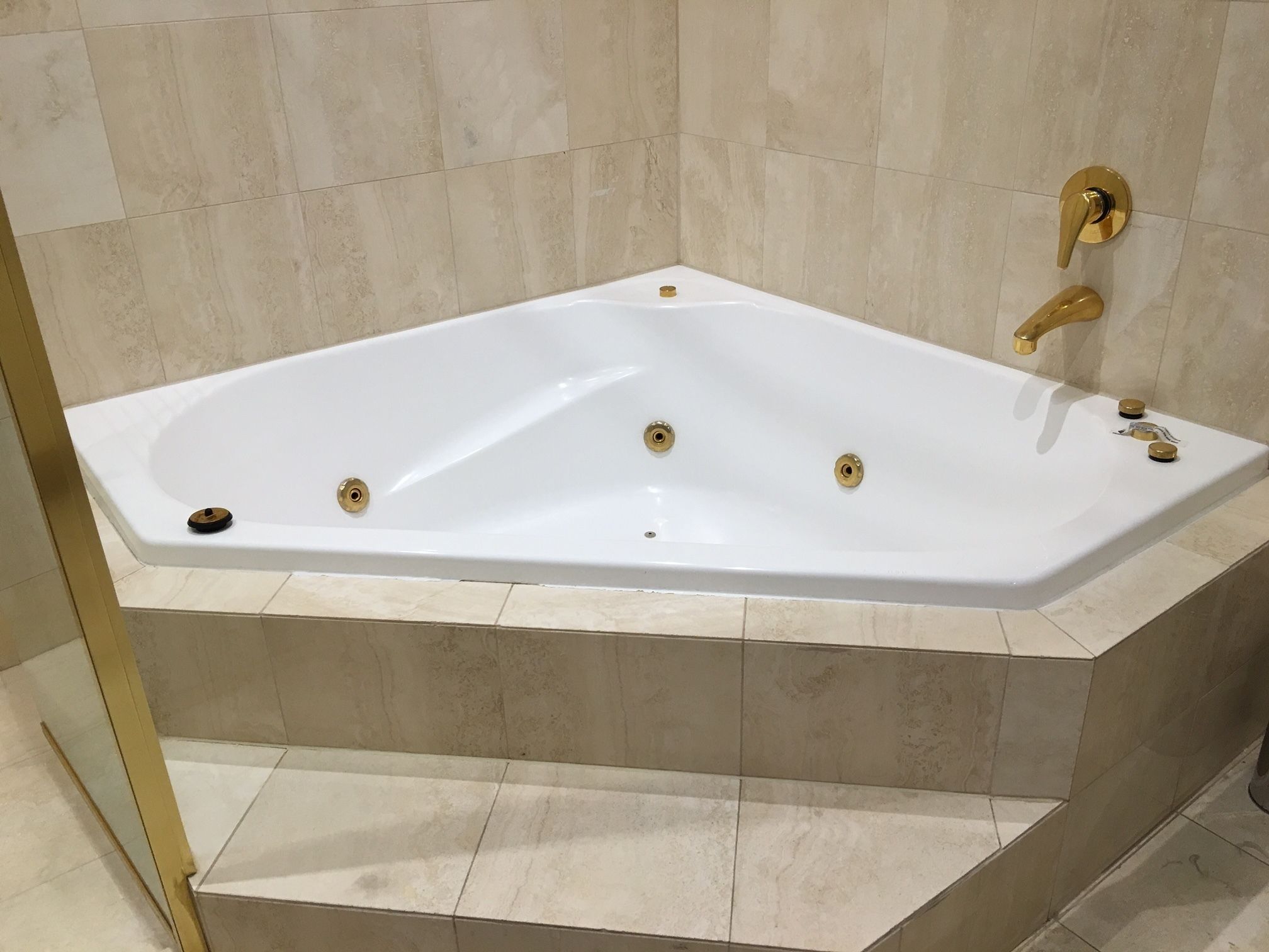 A modern bathroom with a freestanding bathtub, a gold faucet, and a small sink with a gold faucet.