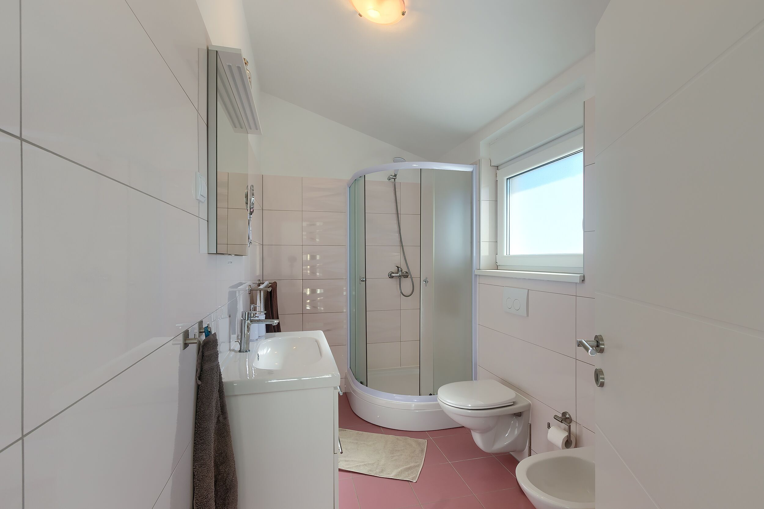 Une salle de bain moderne avec une douche à parois de verre, un lavabo blanc et des toilettes.