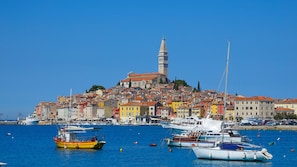 A coastal town with colorful buildings, a prominent tower, and boats in the harbor.