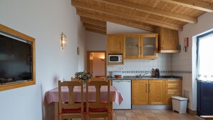 Eine kleine Küche mit Holzausstattung, einer Mikrowelle und einem Essbereich mit kariertem Tischlein.