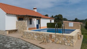 Ein Haus mit Swimmingpool, Steinwänden und einem Ziegeldach.