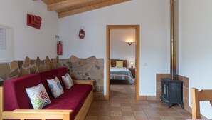 Ein gemütliches Zimmer mit einer Steinwand, einem roten Sofa, einem Holztisch und einem schwarzen Herd.
