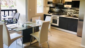 Una cocina moderna con una mesa de comedor de vidrio, sillas y vistas a un balcón.