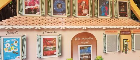 Un bâtiment où sont affichées de nombreuses publicités pour divers événements et spectacles, notamment une soirée karaoké, un salon de l’automobile et une discothèque.