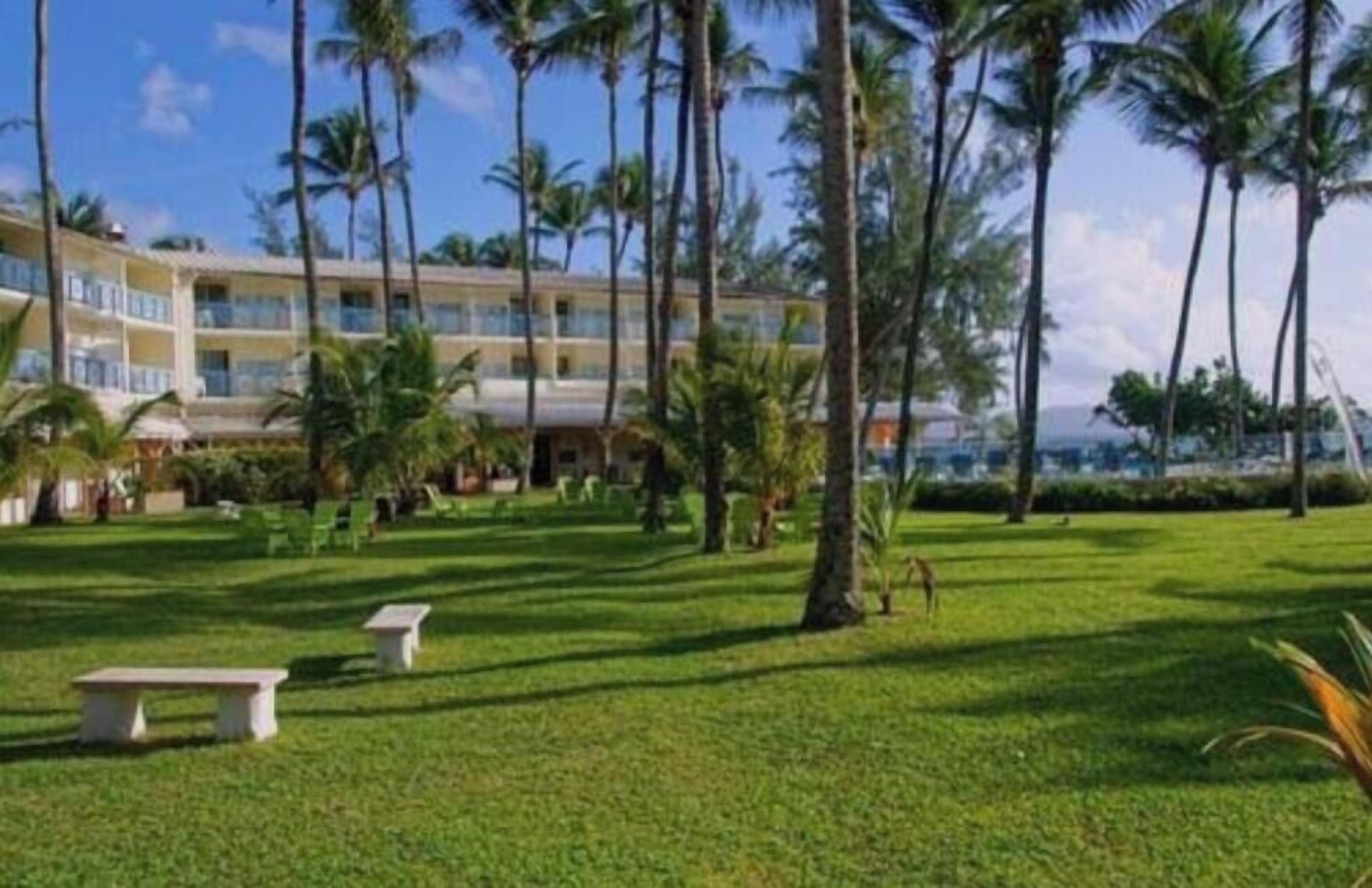 Ein Hotel mit Poolbereich, Palmen und einem Gebäude mit mehreren Balkonen.
