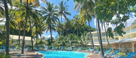 A pool area with lounge chairs and palm trees.