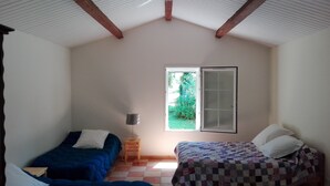 A bedroom with two beds, a window with a view of greenery, and a wooden ceiling. - Small independent house in the countryside, near Saint Emilion, sleeps 4 (Lagorce)