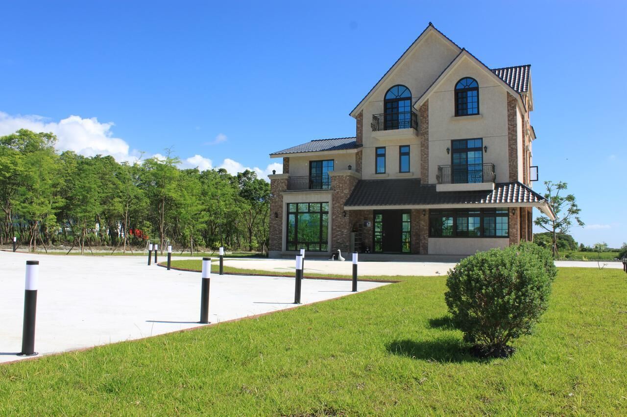 A large, multi-story building with a prominent entrance, large windows, and a landscaped front yard.