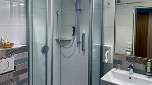 A modern bathroom with a glass-enclosed shower, a white sink, and a mirror. - Wieting (Oldenburg)