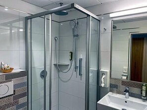 A modern bathroom with a glass-enclosed shower, a white sink, and a mirror. - Wieting (Oldenburg)