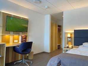 A hotel room with a bed, a desk with a chair, a television, and a wardrobe. - Wieting (Oldenburg)