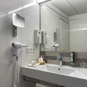 Ein modernes Badezimmer mit Waschbecken, Fön, Handtuch und Spiegel.