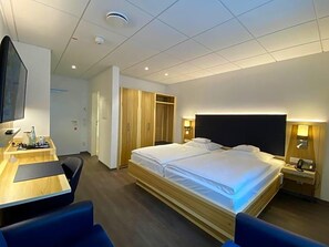 A hotel room with a bed, bedside table, desk, chair, and wardrobe. - Wieting (Oldenburg)