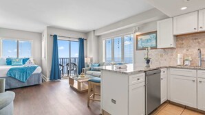 A modern apartment with a kitchen, dining area, and a balcony with blue curtains. - Palace 1503 (Myrtle Beach)