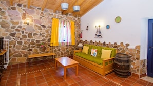 A cozy room with a stone wall, wooden ceiling, a wooden sofa with cushions, a wooden table, and a bench. - Digne Yellow Villa, Pool, BBQ (Aljezur)
