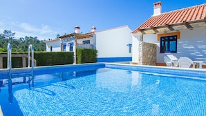 A swimming pool with a clear blue tile, surrounded by white buildings with red-tiled roofs and blue accents. - Digne Yellow Villa, Pool, BBQ (Aljezur)