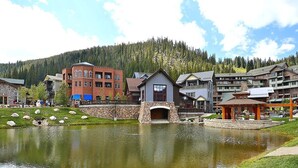 Un hotel sul lago con un ponte in pietra, un gazebo e montagne sullo sfondo.
