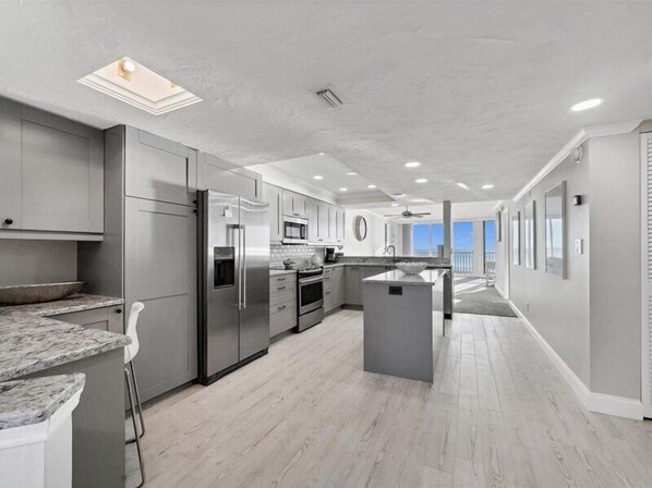 Una cocina moderna con armarios grises, electrodomésticos de acero inoxidable y una isla central.