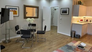 A modern living room with a dining area, a kitchen, and a hallway.
