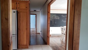 A corridor with wooden cabinets, a refrigerator, and a chalkboard with a tree drawing. - Your comfortable vacation place! (Plattsburgh)