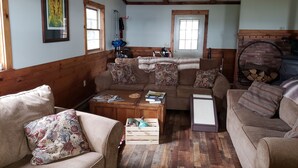 A cozy living room with wooden walls and floors, a sofa set, a coffee table, and a fireplace. - Your comfortable vacation place! (Plattsburgh)