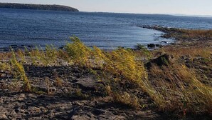 A rocky shoreline with a view of the ocean and a distant landmass. - Your comfortable vacation place! (Plattsburgh)