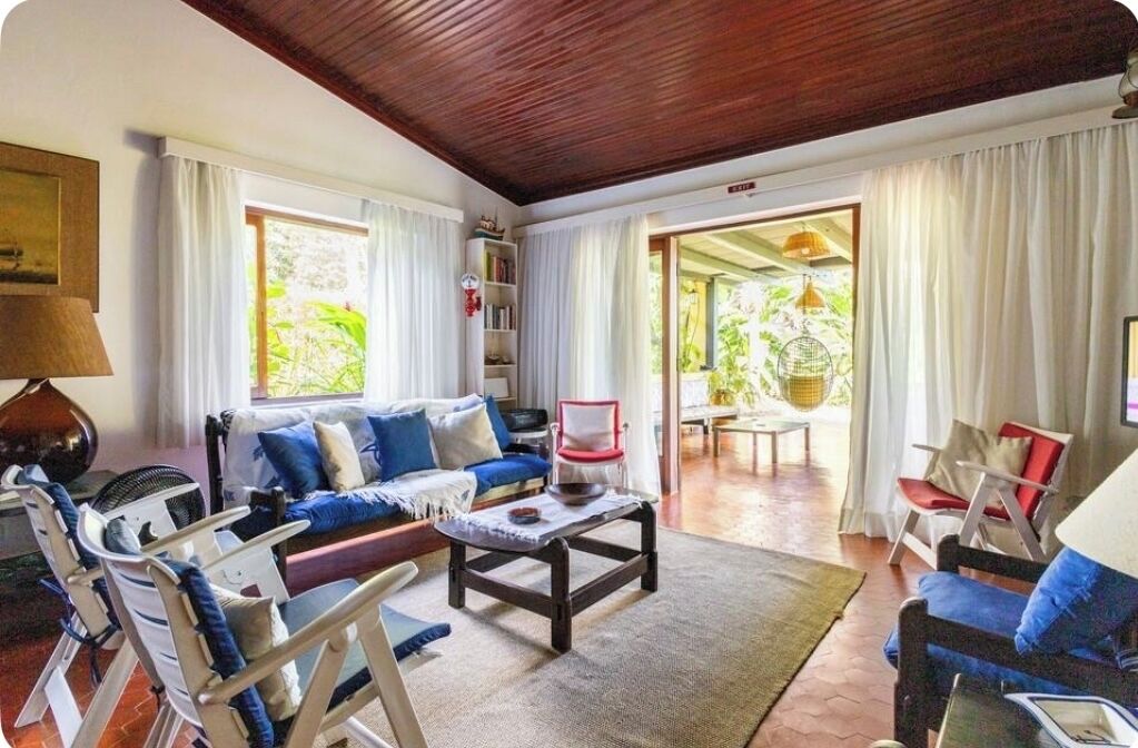 A cozy living room with a wooden ceiling, a sofa set, a coffee table, and a bookshelf.