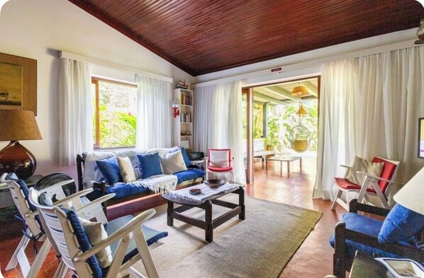 A cozy living room with a wooden ceiling, a sofa set, a coffee table, and a bookshelf.