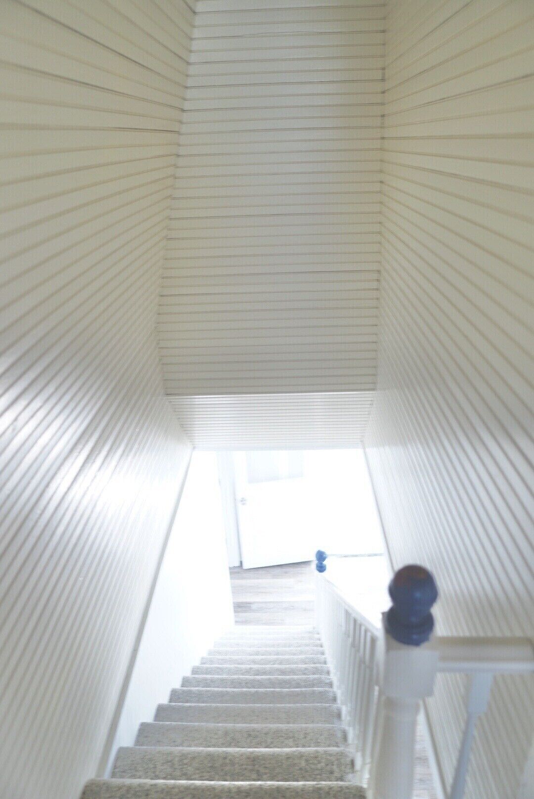 Un escalier avec une rampe blanche et une vue sur une porte en haut.
