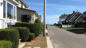 Rua residencial com casas, calçada e céu claro.