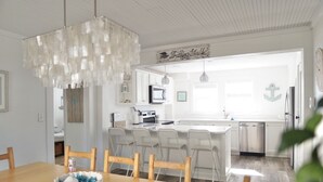 Cozinha moderna com armários brancos, ilha central e iluminação pendente.