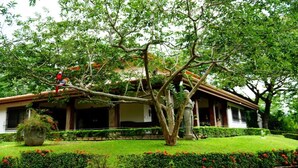 A traditional house with a covered porch, surrounded by well-maintained gardens and trees. - Quinta El Poblado Luxury Home near Jaco Beach (Provincia de Alajuela)