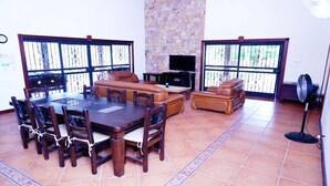 A spacious living area with a dining table, leather sofas, and a TV. - Quinta El Poblado Luxury Home near Jaco Beach (Provincia de Alajuela)