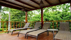 A covered outdoor seating area with lounge chairs and a table, surrounded by lush greenery. - Quinta El Poblado Luxury Home near Jaco Beach (Provincia de Alajuela)