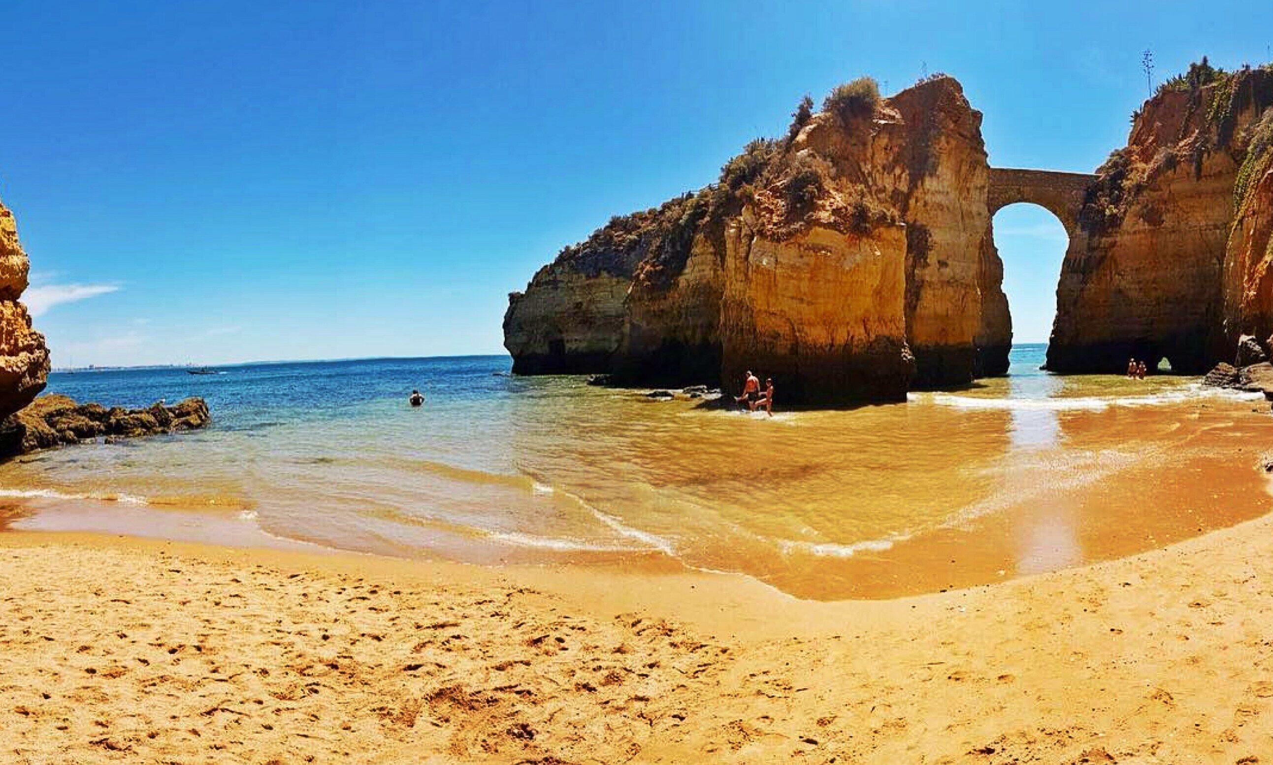 A beach with a natural rock arch formation.