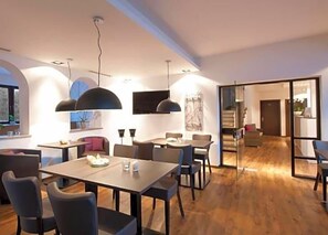 Un comedor moderno con una mesa larga, sillas e iluminación colgante.