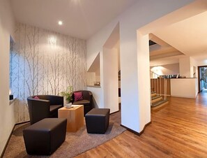 Una sala de estar moderna con un sofá, otomanas y una mesa de centro. Una escalera conduce a un nivel superior.
