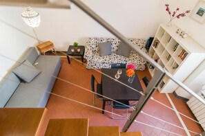 A modern living room with a sofa, a dining table, and a staircase. - Comfortable and bright 80 sqm apartment, able to comfortably accommodate up to 5 people, is located on the third and top floor of a late 19th century building with lift. The property is located in an elegant neighborhood near the historic center of Flore (Firenze)