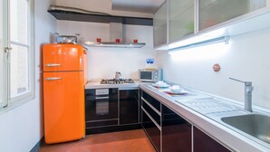 Una cocina compacta con estufa a gas, microondas, pileta y refrigerador.