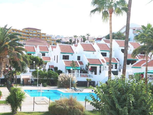 A resort with white buildings, red-tiled roofs, and a swimming pool.
