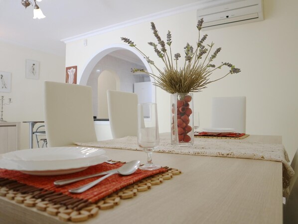 Una mesa puesta con platos, cubiertos y un florero con plantas secas.