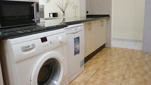 A compact kitchen with a washing machine, microwave, and a small sink. - Sunny Villa Holiday Home (Torviscas Bajo)