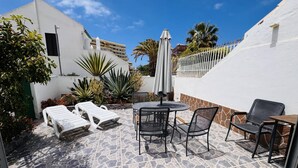A patio with a stone floor, a round table with chairs, and a white umbrella. - Sunny Villa Holiday Home (Torviscas Bajo)