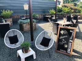An outdoor seating area with wicker chairs, a small table, and a chalkboard sign.
