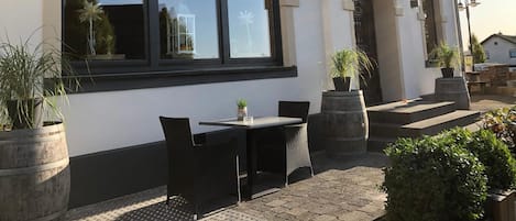 A hotel exterior with a sign reading 'Hotel Typisch,' outdoor seating with chairs and a table, and potted plants.