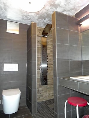 A modern bathroom with a shower, a toilet, and a sink.