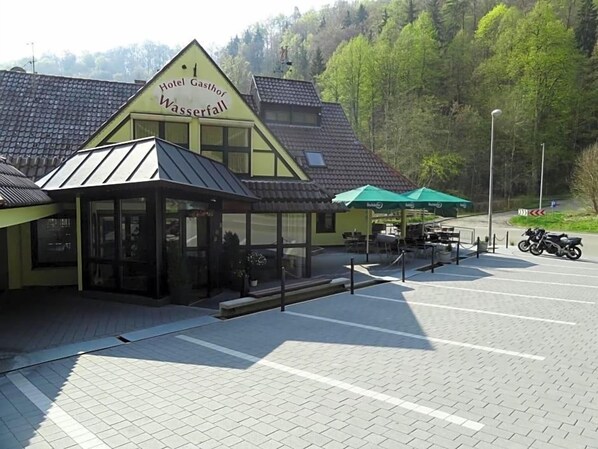 A hotel named 'Hotel Gasthof Wasserfall' with a covered outdoor seating area and a motorcycle parked nearby.