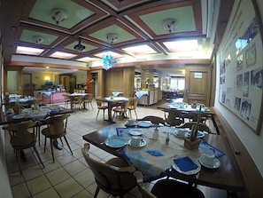 A dining area with multiple tables and chairs, a ceiling with skylights, and a wall with informational posters.